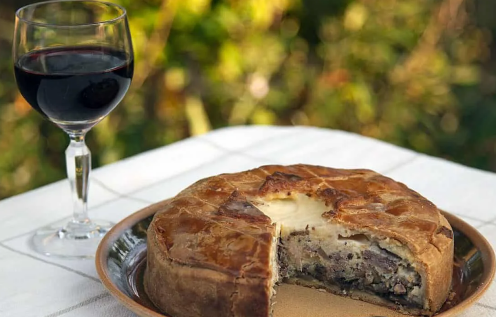 Tourte artisanale accompagnée d'un verre de vin rouge, symbole des spécialités regionales.